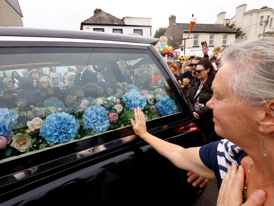 Eine Frau berührt den Wagen, der den Leichnam von Sinead O'Connor trägt