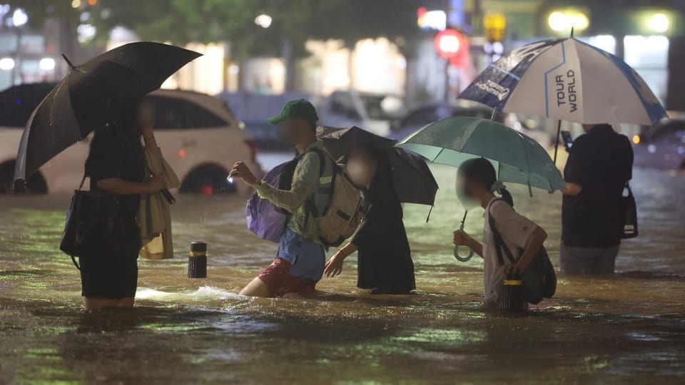 Menschen waten durch die überschwemmten Strassen Seouls