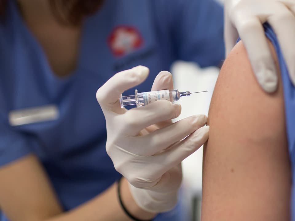 Patientin bei einer Impfung mit hochgekrämpeltem Pulli