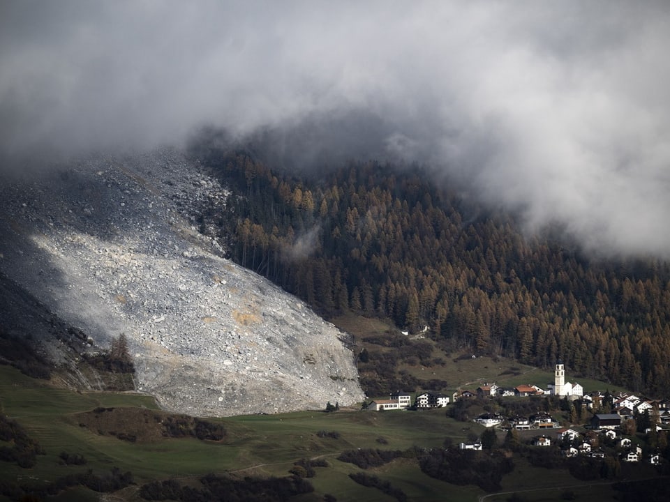 Berge mit Wolken und Dorf im Tal.