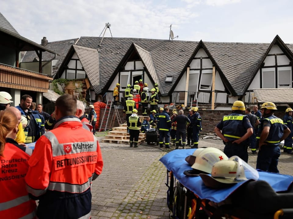 Einsatzkräfte vor einem beschädigten Gebäude.