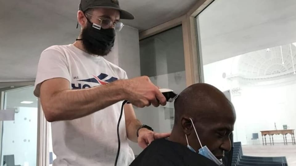 Ein Coiffeur schneidet die Haare eines Kunden in der Kirche