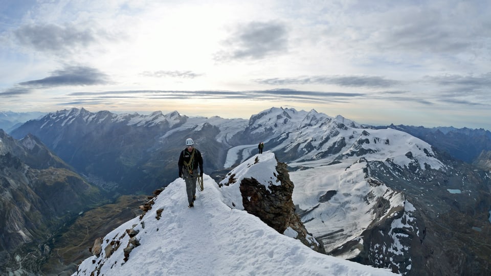 Ein Bergsteiger auf einem verschneiten Grat.