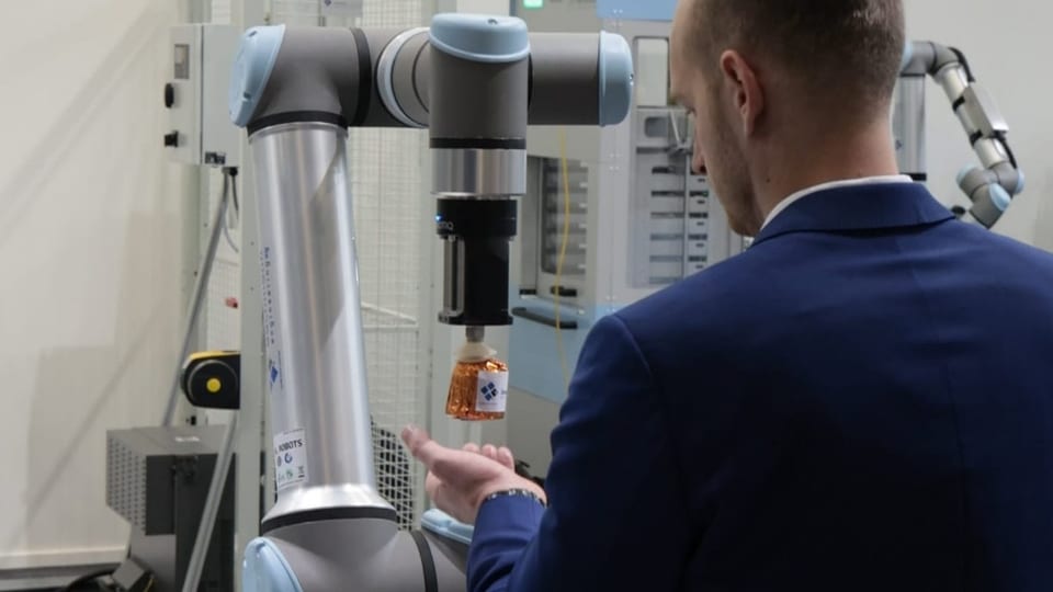 Roboter-Greifarm hält einem Mann einen Dobler-Kopf hin