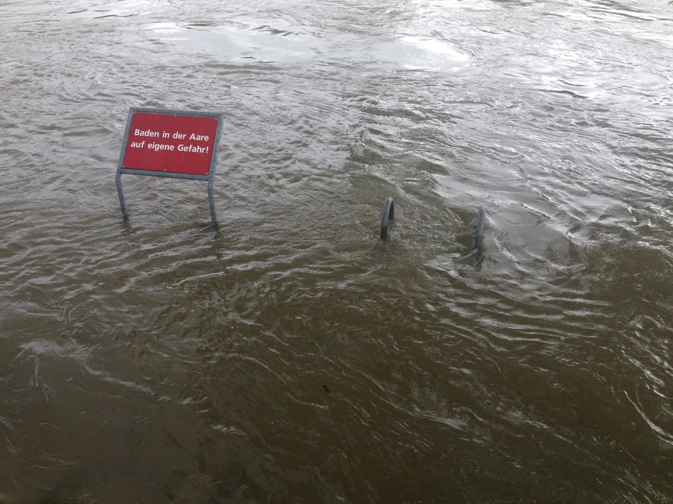 Ein Schild und eine Treppe ragen aus den Wassermassen. 