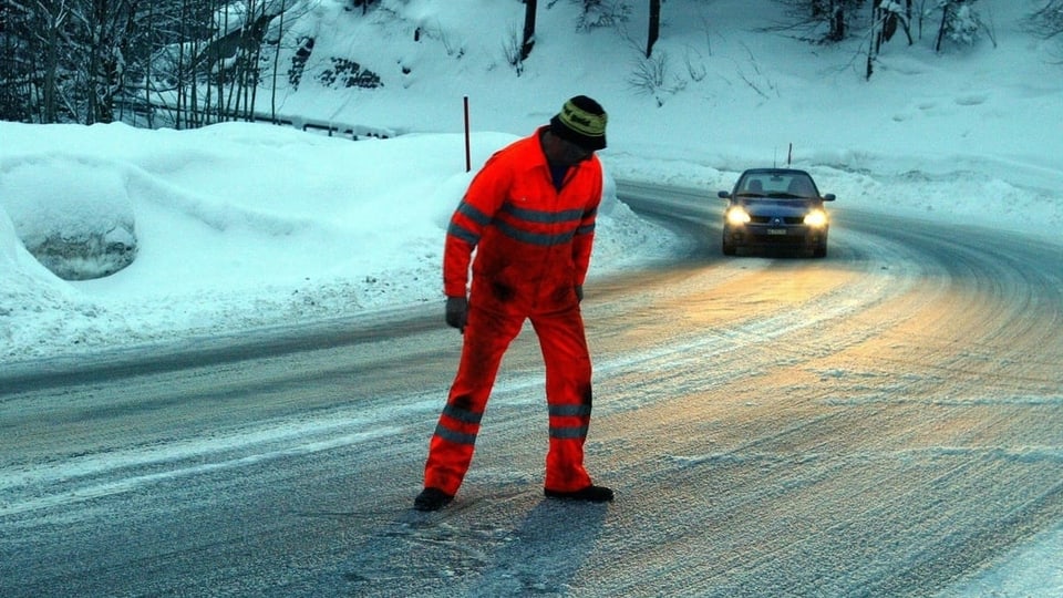 Mann in oranger Kleidung auf vereister Strasse.