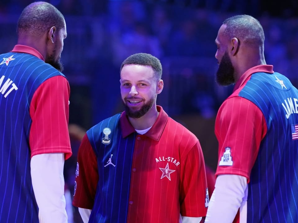 Drei Basketballspieler in All-Star-Trikots auf dem Spielfeld.