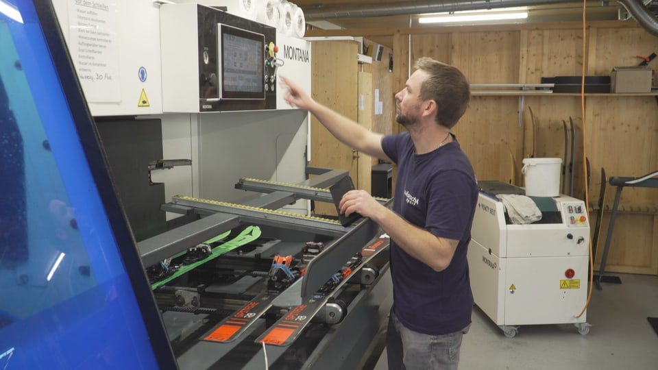 Mann bedient Skiservice-Maschine in der Werkstatt.