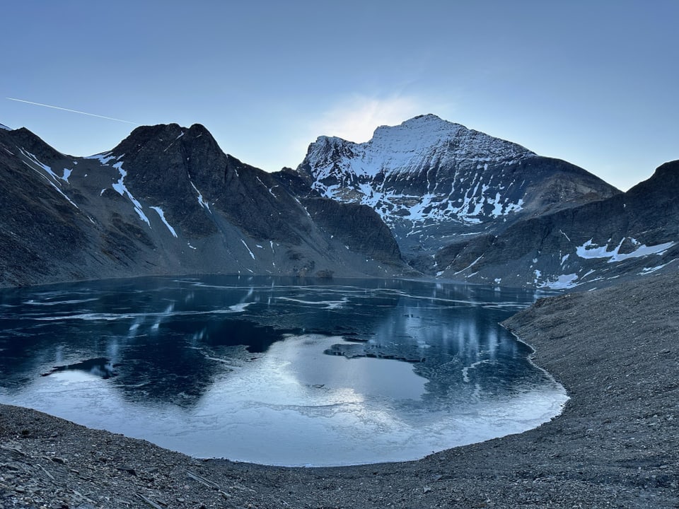 Bergsee vor schneebedeckten Bergen bei Sonnenuntergang.