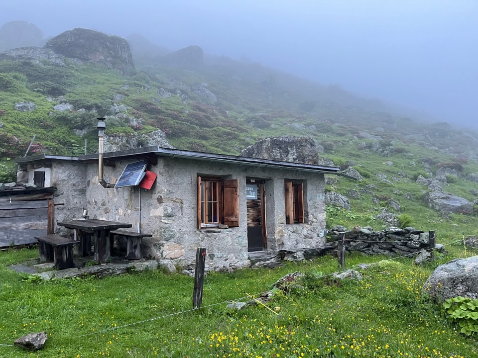 Steinhaus in nebliger Berglandschaft.