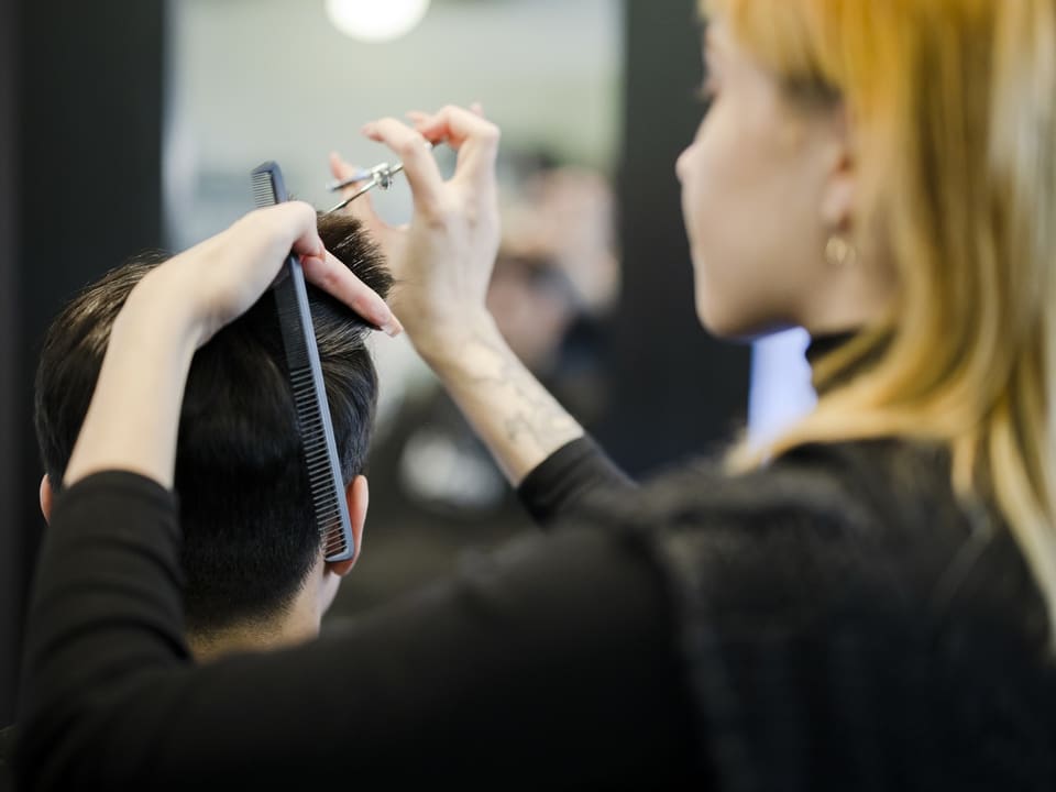 Friseur schneidet Haare eines Kunden mit Schere und Kamm.