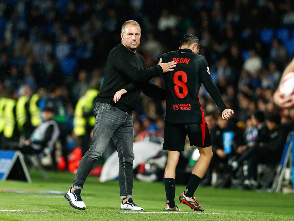 Trainer berührt Spieler am Spielfeldrand.