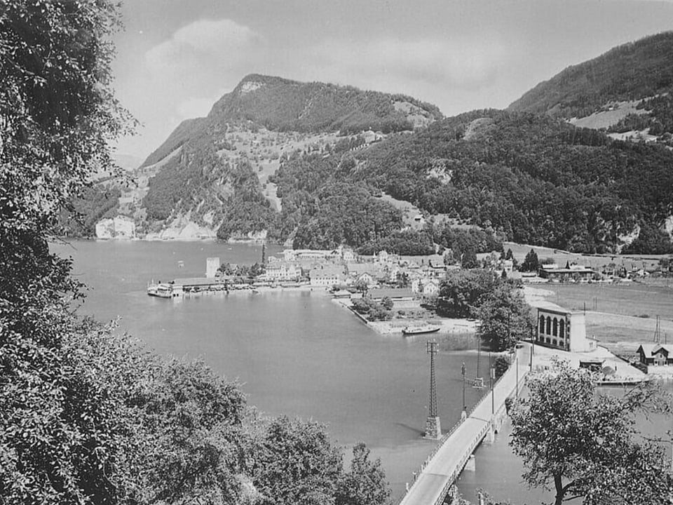 Landschaft mit See, Bergen und Brücke.