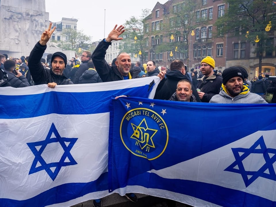 Menschen halten israelische und Sportverein-Flaggen hoch.