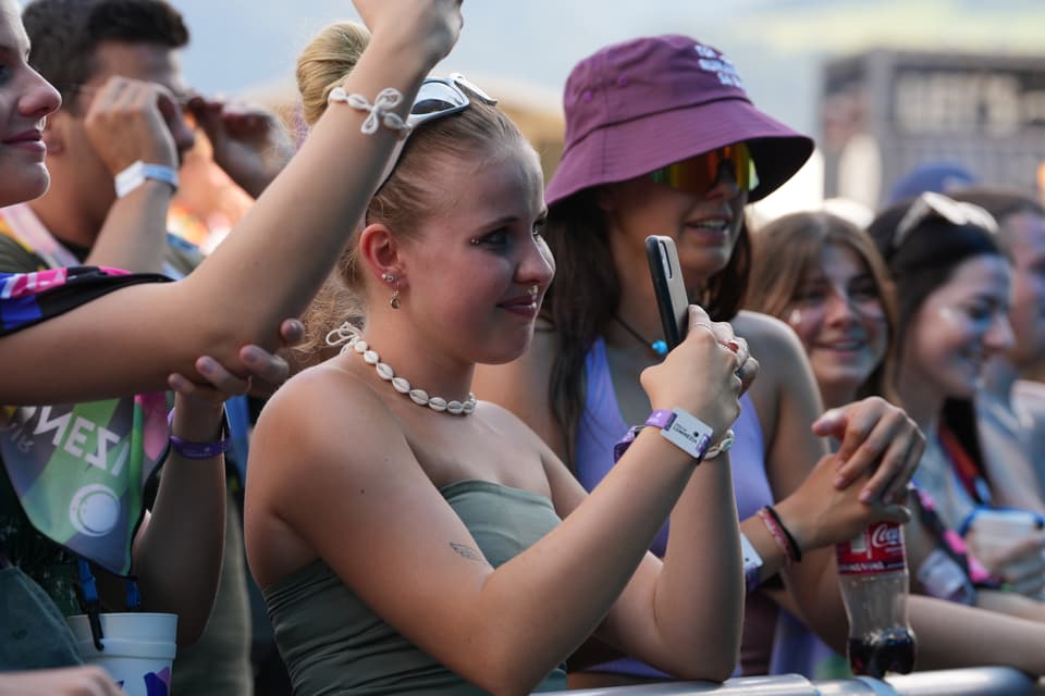 Menschenmenge auf einem Festival, Frau hält Smartphone am Open Air Lumnezia 2024.