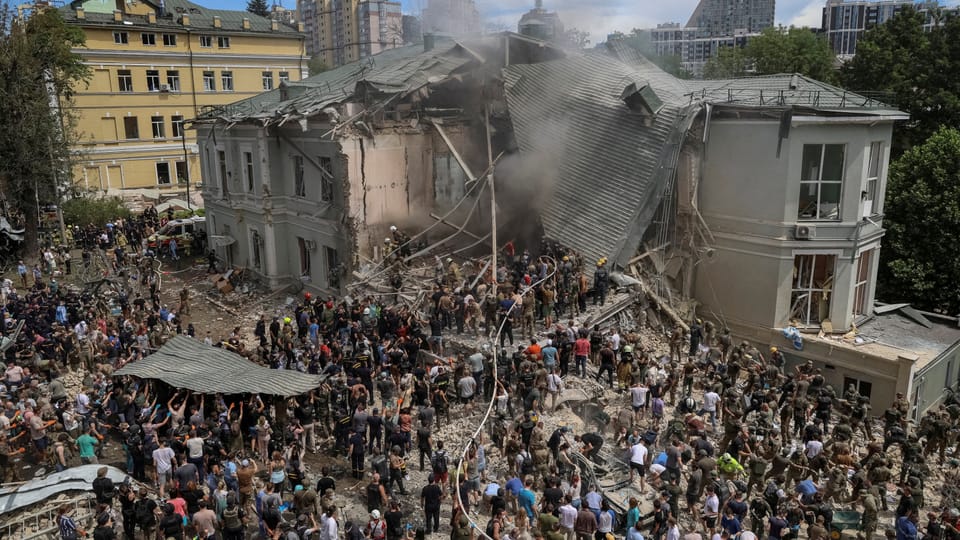 Menschenmenge vor teilweise eingestürztem Gebäude.