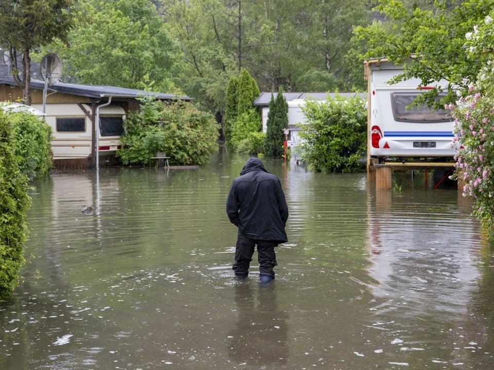 Mann watet durch überschwemmten Campingplatz
