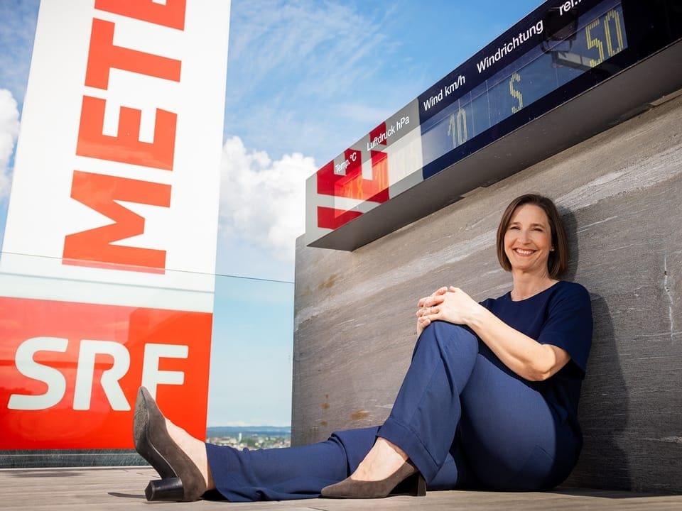 Frau sitzt vor Wetteranzeige mit SRF-Logo.