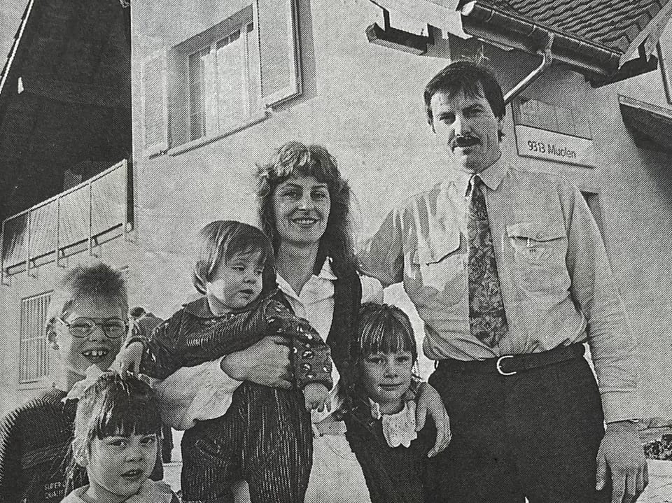 Schwarz-Weiss-Foto einer Familie vor einem Haus.