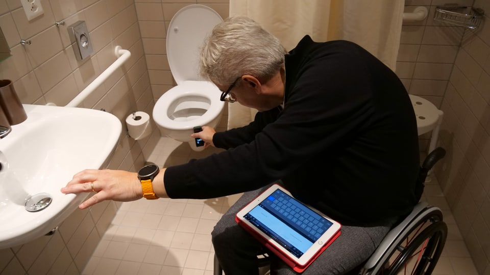 Der Rollstuhlfahrer vermisst mit einem elektronischen Gerät das Badezimmer.