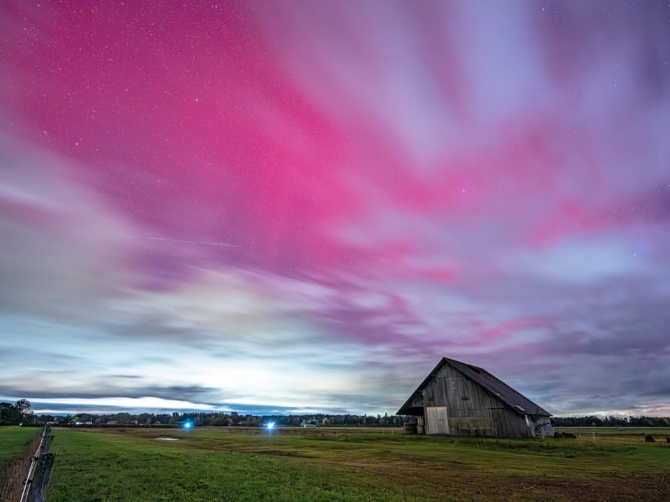 Scheune unter leuchtendem Himmel mit rosa und violetten Wolken.