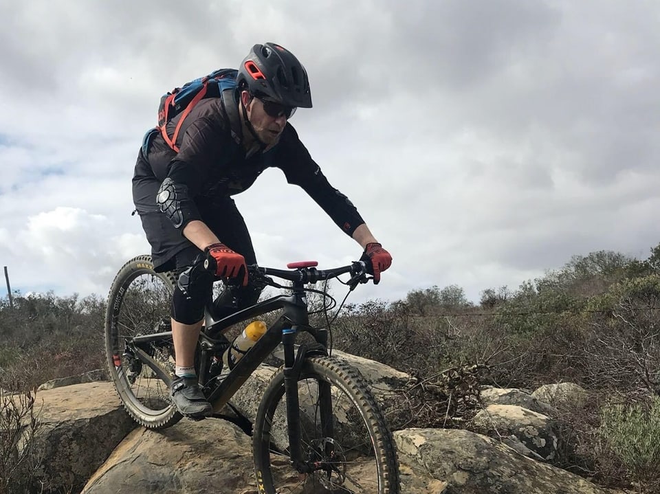 Mann mit Helm fährt Mountainbike über Felsen.