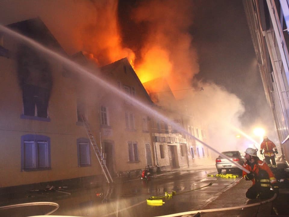 Flammen züngeln über dem Dach des Gebäudekomplexes.