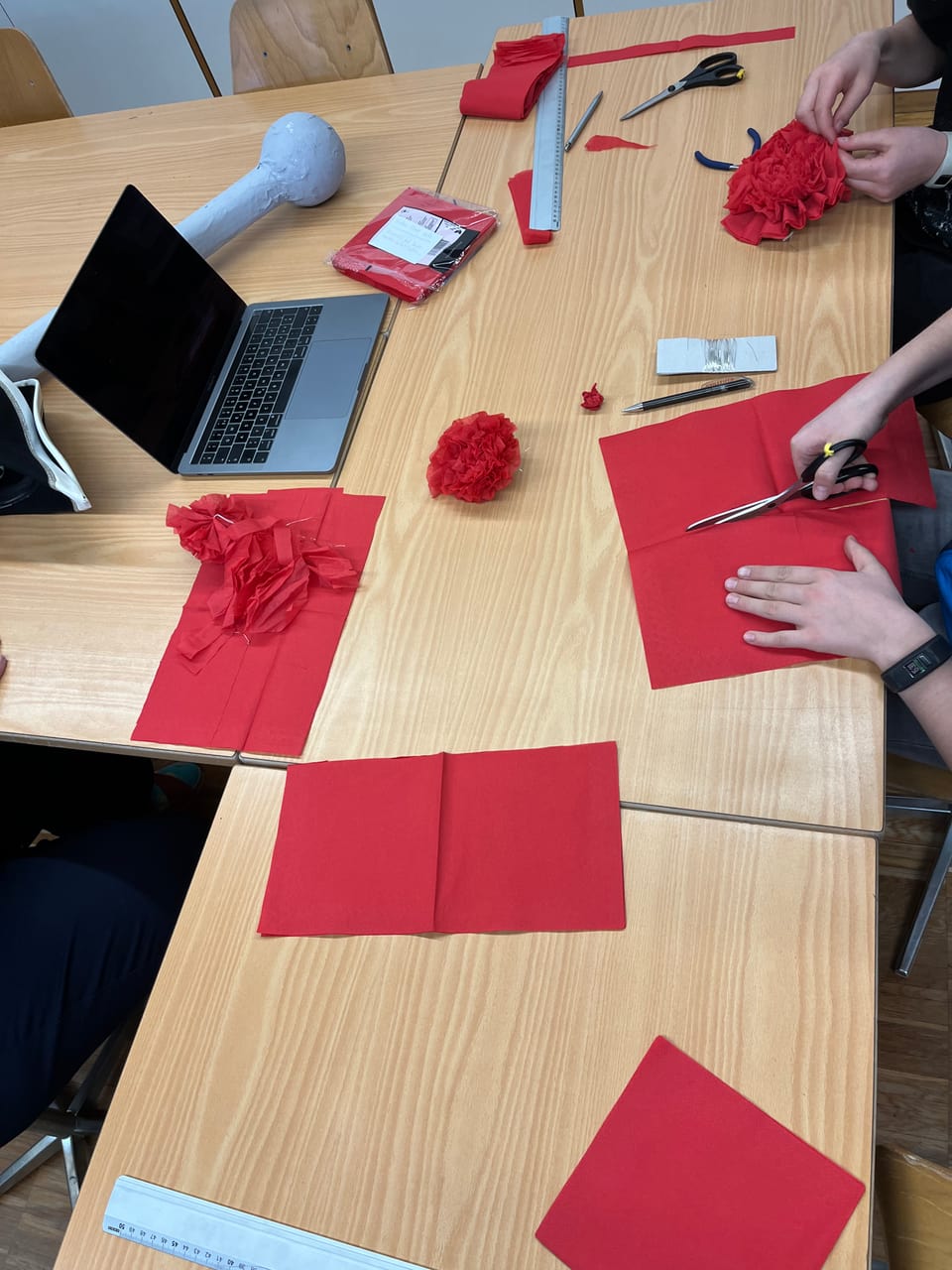 Die Kinder schneiden rote Blumen aus Servietten.