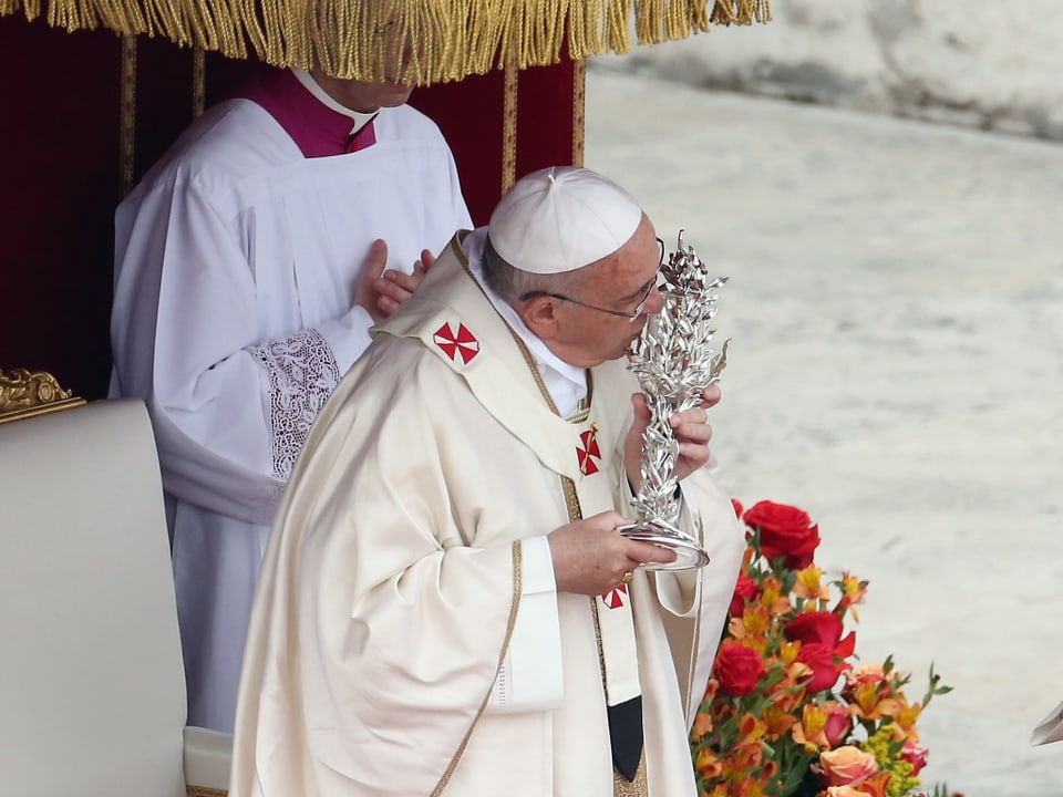 Der Papst in weissem Gewand küsst eine silberne Reliquie.