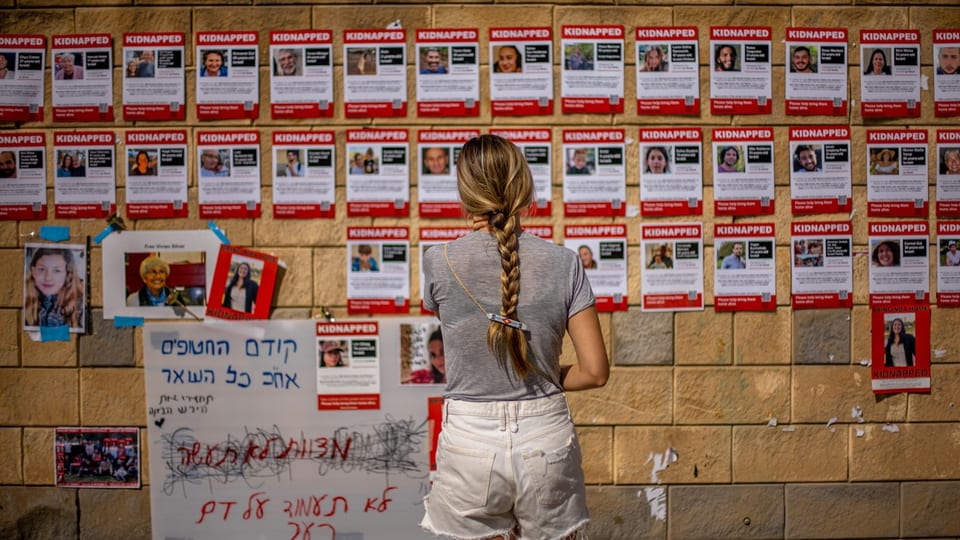 Eine Frau steht vor einer Wand mit Fotos von Vermissten.