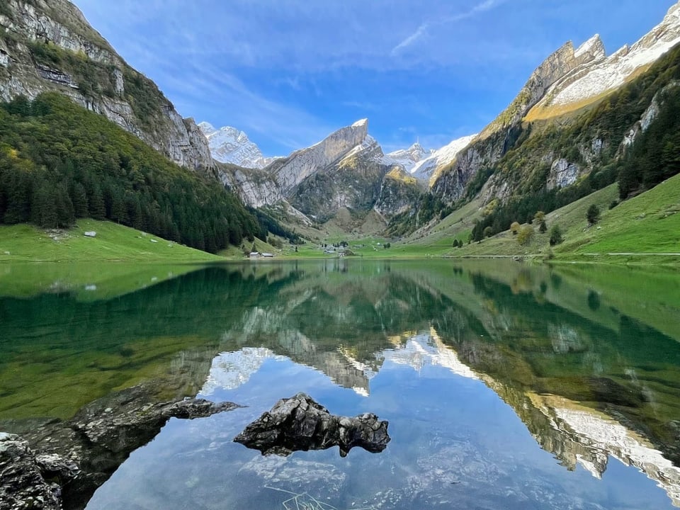 Bergsee mit Bergspiegelung unter klarem Himmel.