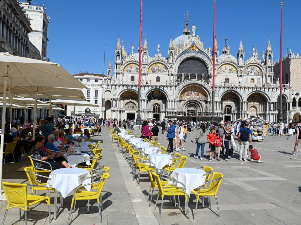 Café-Stühle und Tische auf dem Markusplatz vor der Basilika in Venedig.