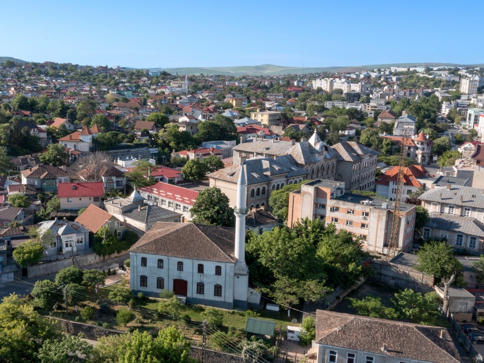 Luftaufnahme einer Stadt mit Häusern, Bäumen und Gebäuden.