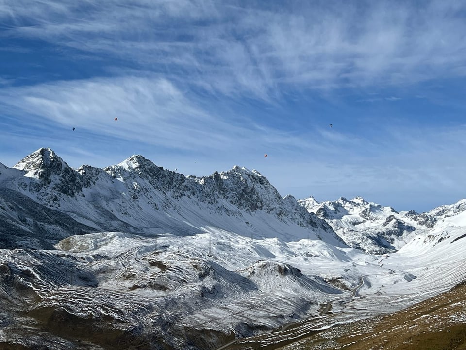 Verschneite Berge unter blauem Himmel mit Wolken.