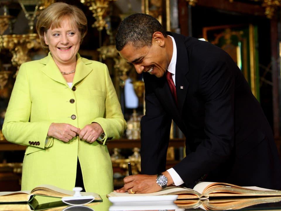 Merkel neben Obama, der sich ins Goldene Buch der STadt Dresden einträgt.