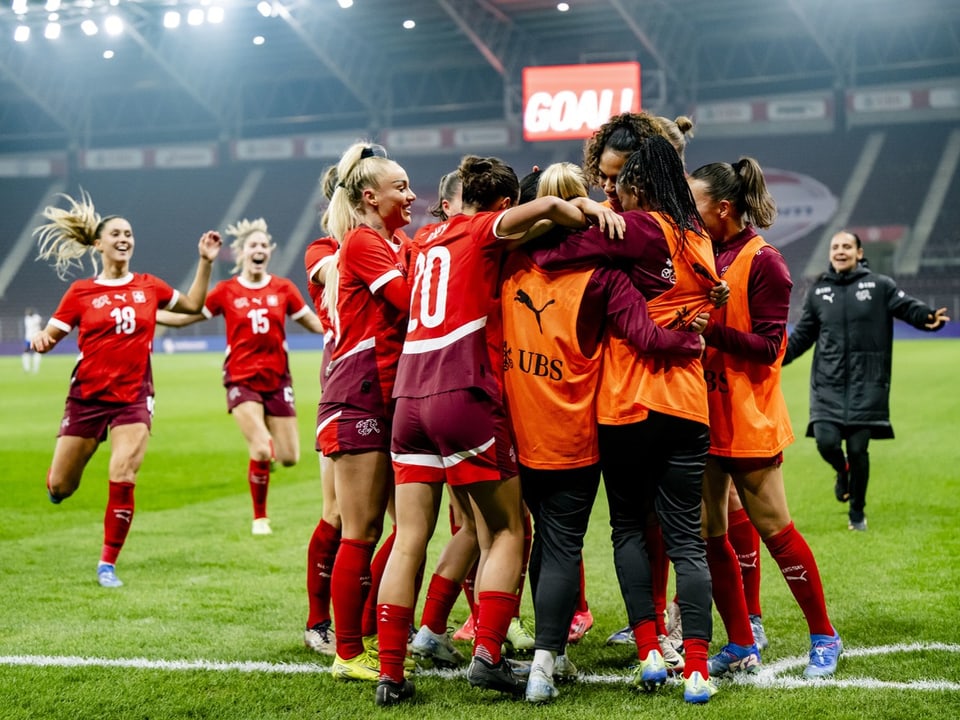 Jubelnde Frauenfussballmannschaft auf dem Spielfeld.