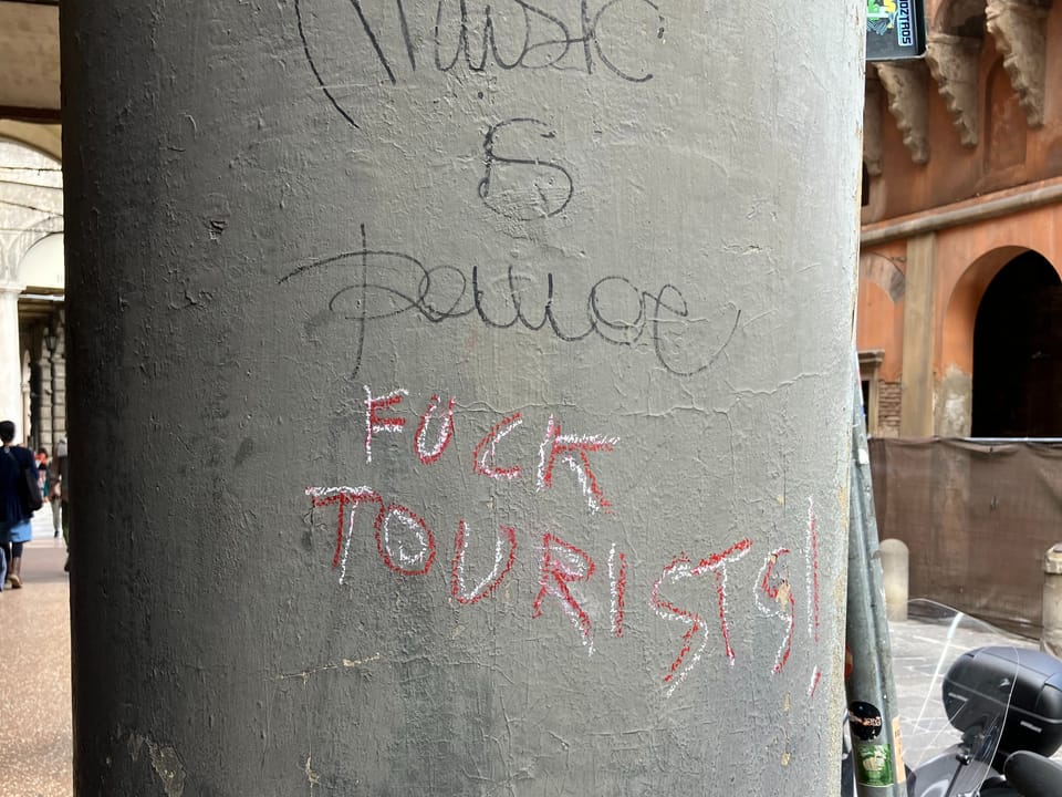 Pfeiler mit Graffiti gegen Touristen.
