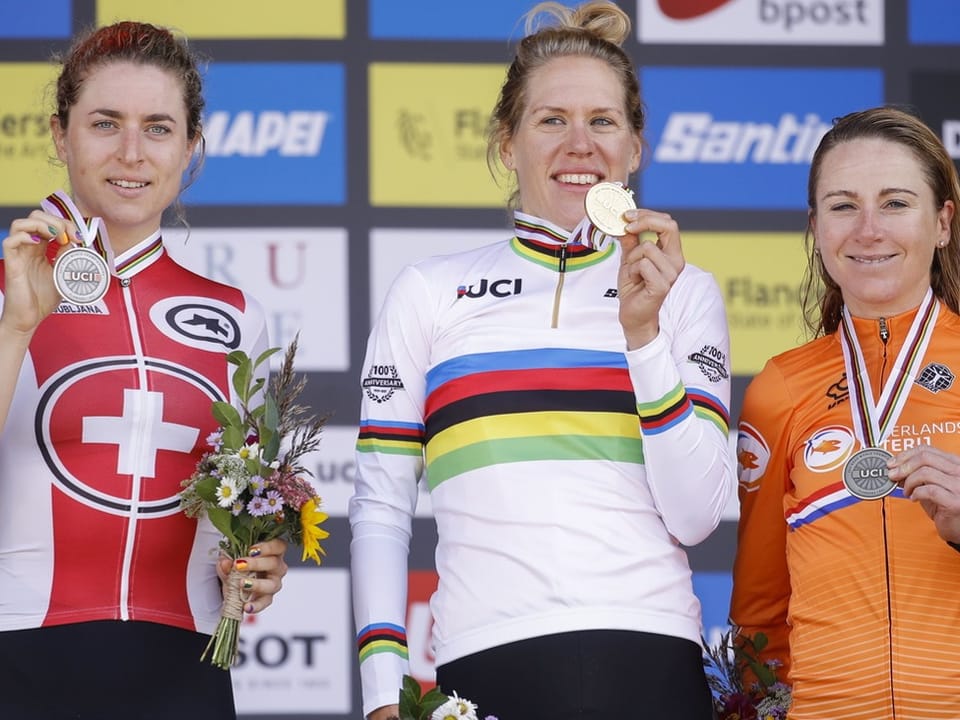 Drei Radfahrerinnen auf dem Podium mit Medaillen und Blumensträussen.