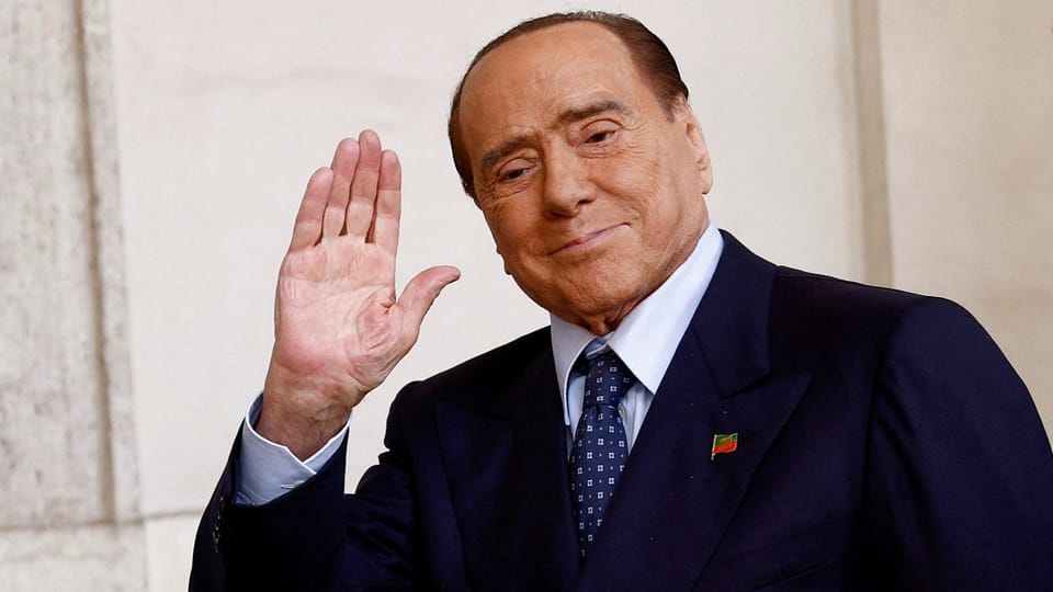 Silvio Berlusconi im Anzug winkt.