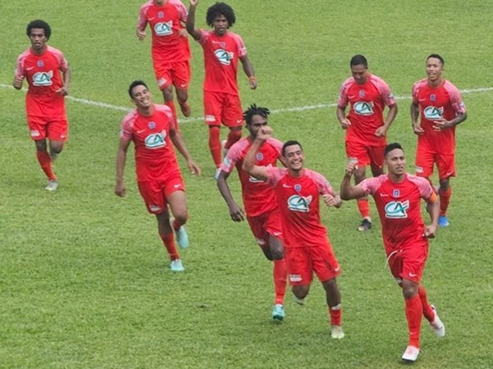 Fussballspieler in roten Trikots jubeln auf dem Spielfeld.