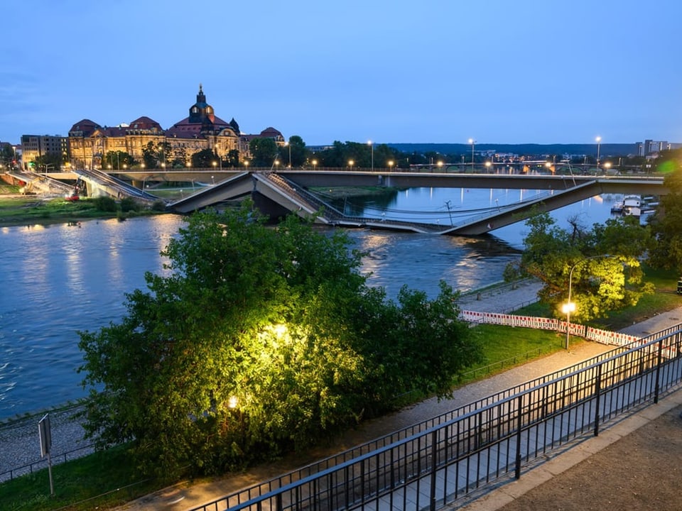 Abendblick auf eine beleuchtete Brücke über einen Fluss.