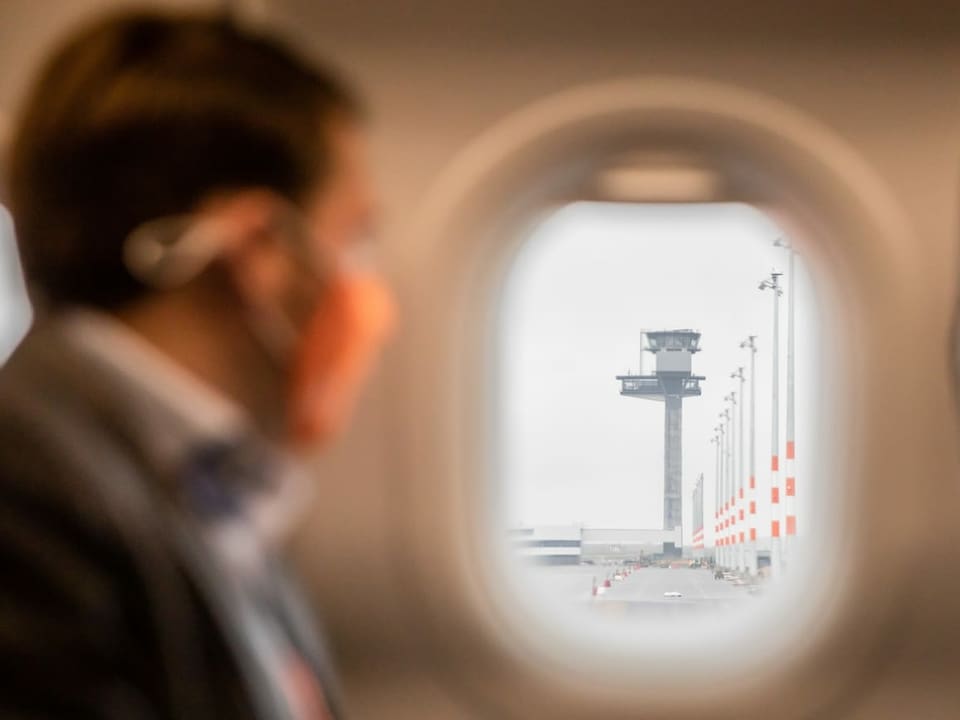 Mann mit oranger Maske schaut aus dem Fenster und sieht den Tower.