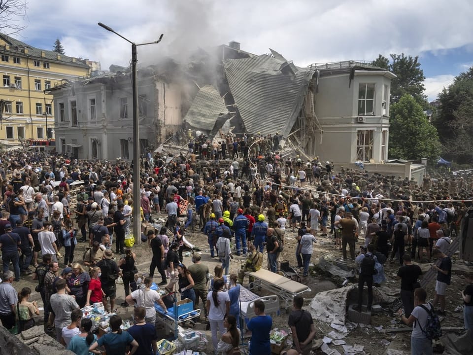 Menschenmenge vor einem eingestürzten Gebäude.