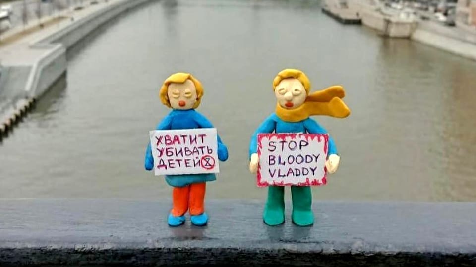 Zwei Knetfiguren mit Protestschildern in den Händen stehen auf einer Brücke.