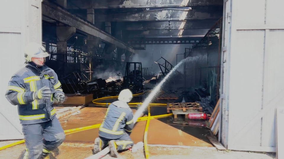 Feuerwehrleute löschen den Brand im Warenlager.