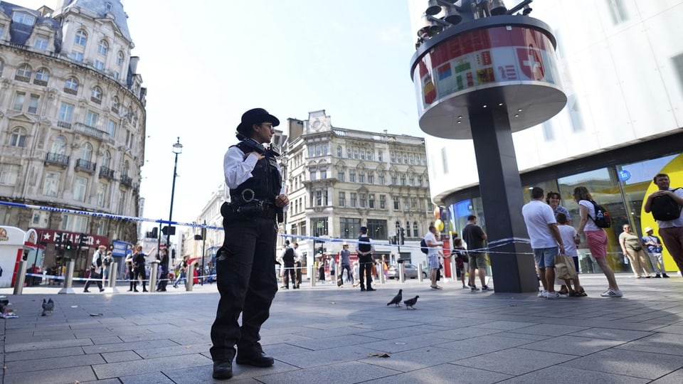 Polizeibeamter überwacht abgesperrten Bereich in belebter Stadt.