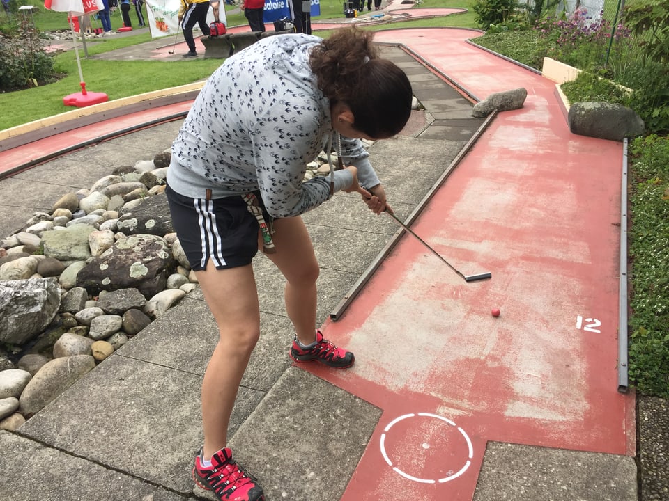 Eine Minigolfspielerin ist hochkonzentriert am Abschlag