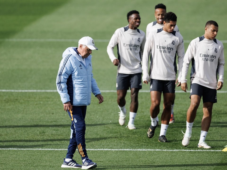 Fussballtrainer leitet Training mit Spielern auf dem Feld.