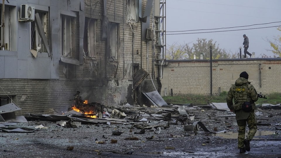 Ein russischer Soldat läuft an brennenden Trümmern vorbei