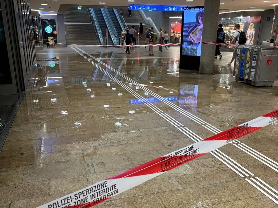 Überfluteter Bahnhofbereich mit Absperrband der Polizei.